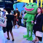 Attendees at Dubai’s Token2049 conference pause for a picture with a mascot for meme coin Pepe the frog on Wednesday. (Giuseppe Cacace /AFP via Getty Images)