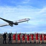 Virgin Australia cabin crew wave goodbye to the inaugural VA1 service from Sydney to Doha beside the runway at Sydney International Airport on Thursday. Virgin Australia is returning to international long-haul flights through an alliance with Qatar Airways five years after the pandemic forced it into administration and two years since Qatar Airways was initially blocked from expanding in Australia. (James D. Morgan/Getty Images for Virgin Australia)
