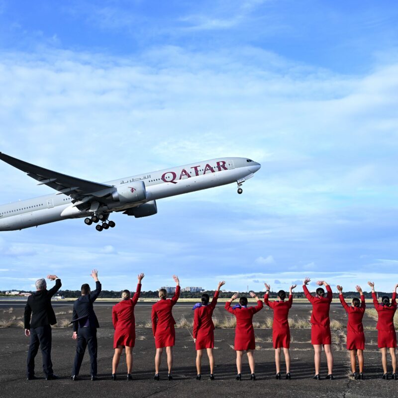 Virgin Australia cabin crew wave goodbye to the inaugural VA1 service from Sydney to Doha beside the runway at Sydney International Airport on Thursday. Virgin Australia is returning to international long-haul flights through an alliance with Qatar Airways five years after the pandemic forced it into administration and two years since Qatar Airways was initially blocked from expanding in Australia. (James D. Morgan/Getty Images for Virgin Australia)