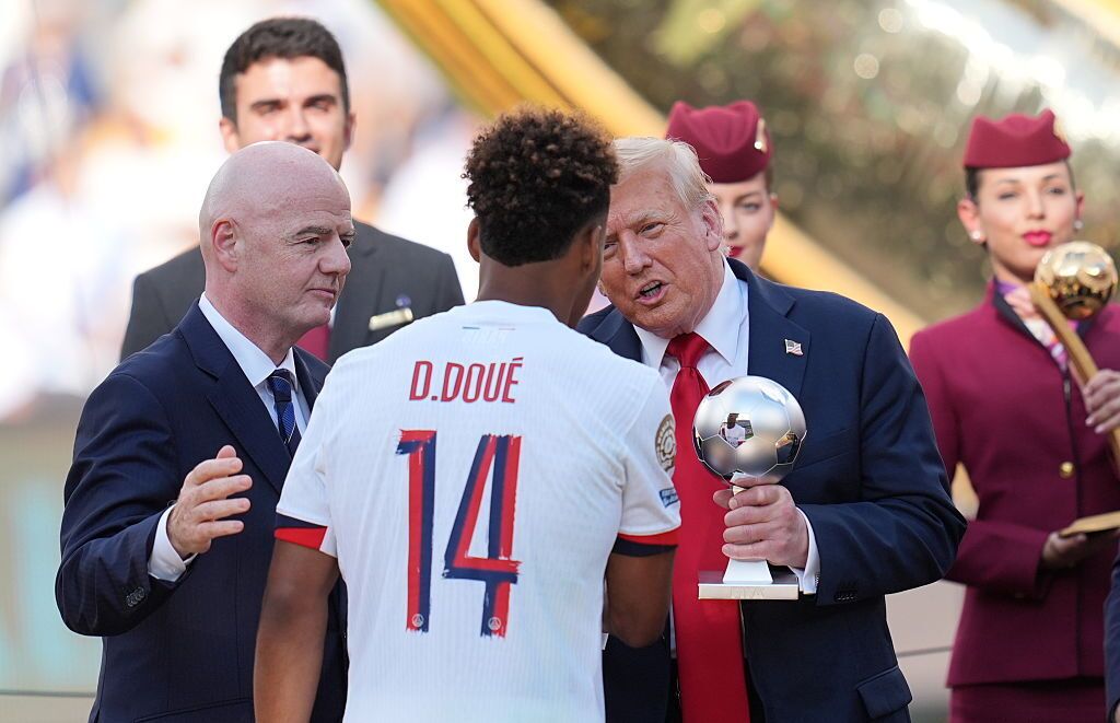 U.S. President Donald Trump presents Paris Saint-Germain's French midfielder Desire Doue with the Young Player Award after the FIFA Club World Cup 2025 final soccer match between England’s Chelsea and France’s PSG, which is majority owned by a subsidiary of the Qatar Investment Authority, at MetLife Stadium, New Jersey. Qatar Airways flight attendants carried the trophies and medals on stage for the ceremony. (AFP via Getty Images)
